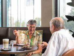 Zwei Personen sitzen am Tisch und essen Dessert