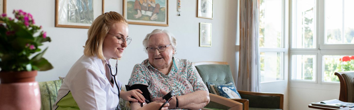 Pflegerin misst Bewohnerin Blutdruck
