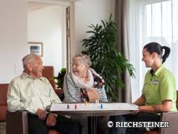 Zwei Bewohnende spielen mit einer Frau ein Brettspiel