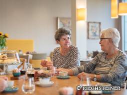 Zwei Frauen sitzen gemeinsam am Tisch und geniessen ein Kaffee
