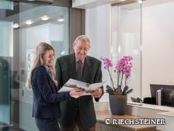 Mitarbeitende zeigt Bewohnendem etwas in der Zeitschrift