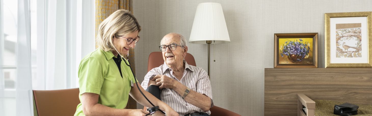 Mitarbeiterin misst Bewohner Blutdruck