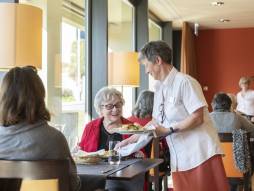 Frau serviert Essen an zwei Personen