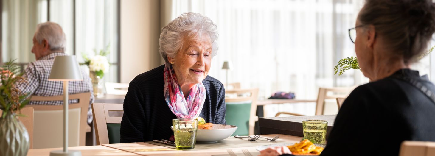Zwei Herren am Tisch werden vom Servicepersonal zum Mittagessen bedient