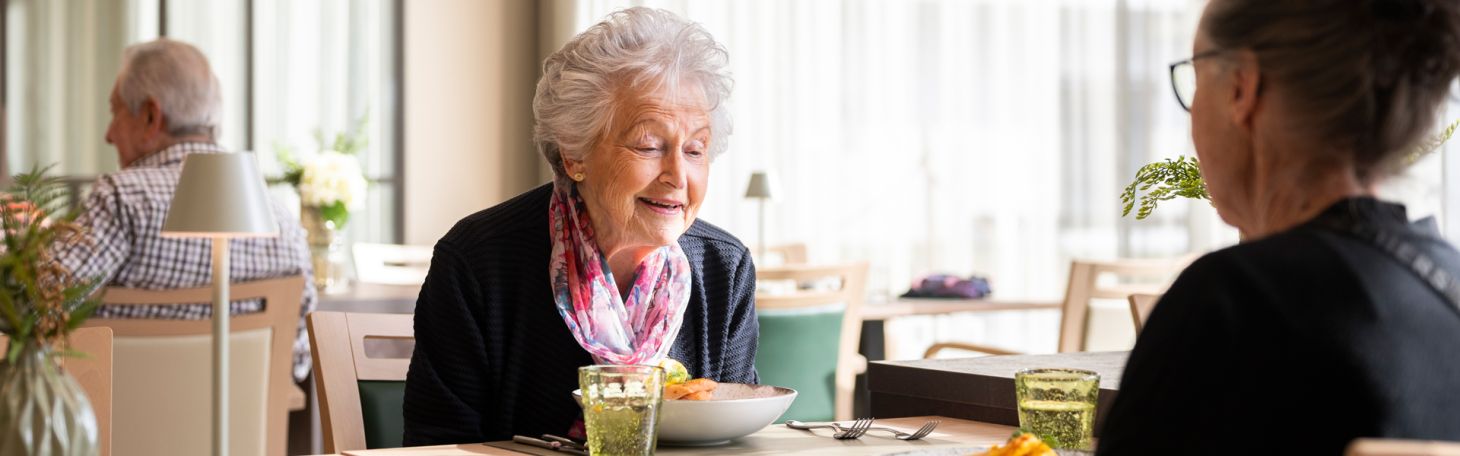 Zwei Herren am Tisch werden vom Servicepersonal zum Mittagessen bedient