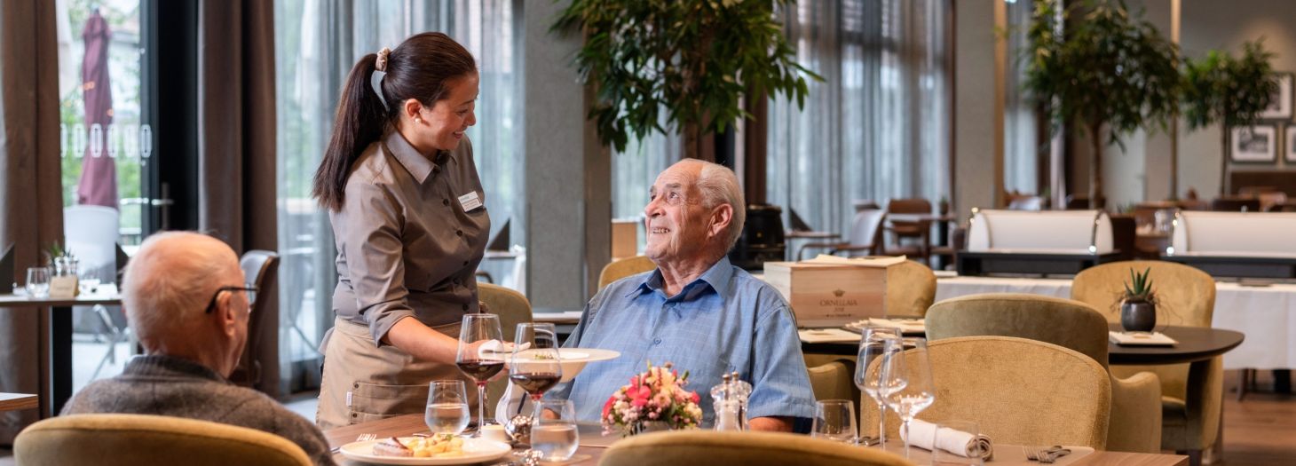 Zwei Herren am Tisch werden vom Servicepersonal zum Mittagessen bedient