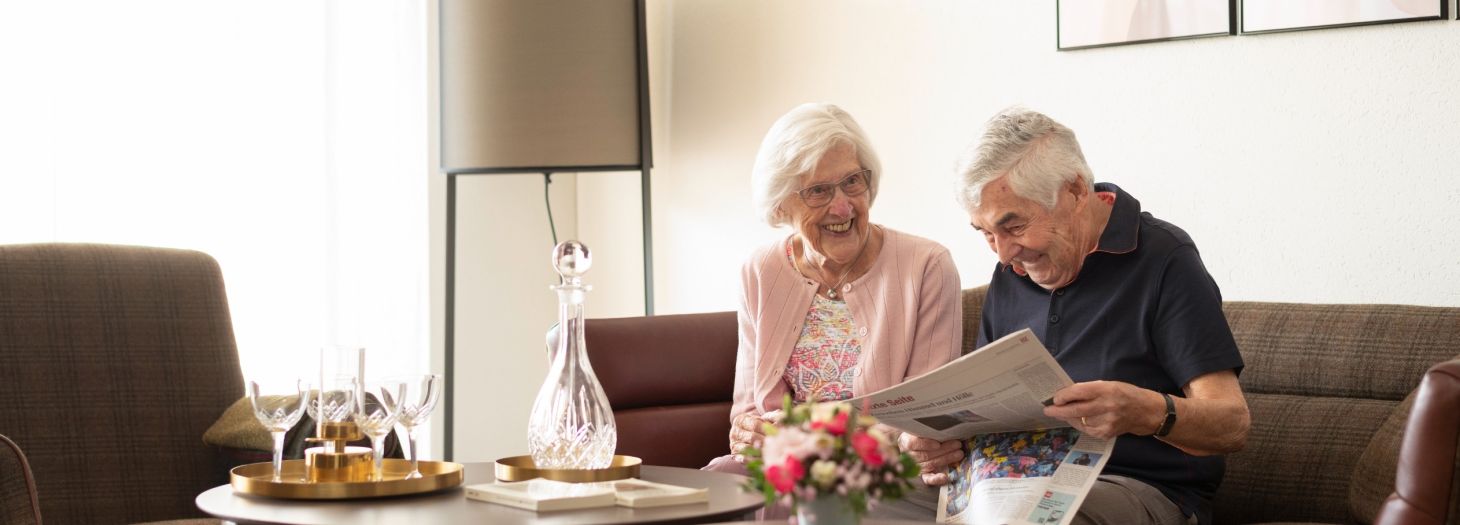 Zwei Personen auf der Couch am Magazin lesen