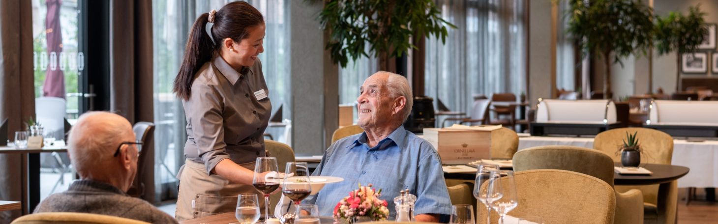 Zwei Herren am Tisch werden vom Servicepersonal zum Mittagessen bedient