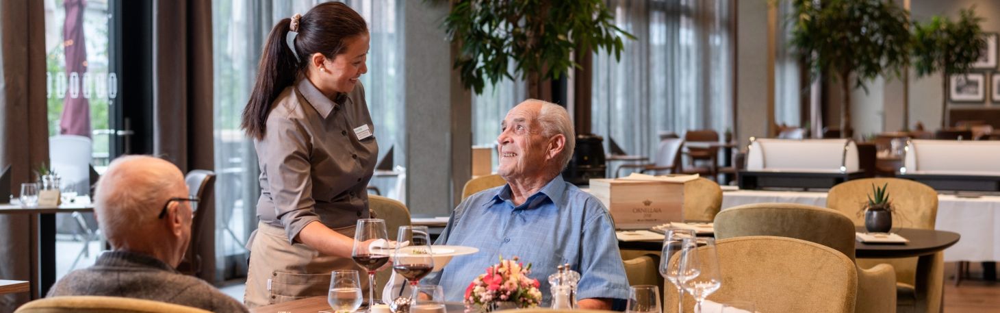 Zwei Herren am Tisch werden vom Servicepersonal zum Mittagessen bedient