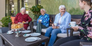 4 Personen am Kuchen essen und Kaffee trinken