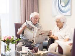 Zwei Personen am Sessel und Lesen die Zeitung