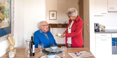 Frau serviert Mann Kaffee am Esstisch