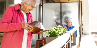 Dame giesst Blumen auf dem Balkon