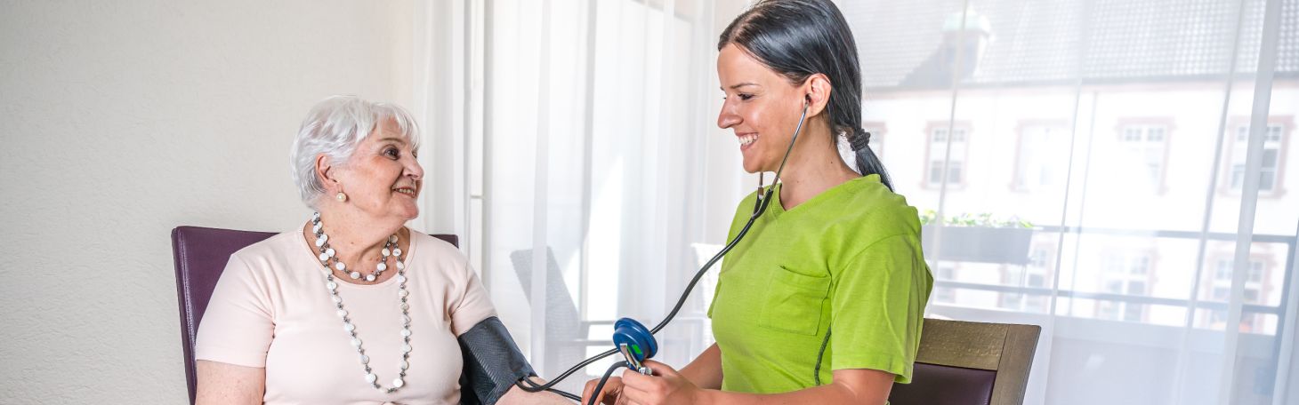 Pflegerin misst Bewohnerin Blutdruck