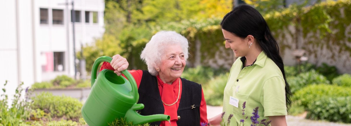 Pflegerin mit Bewohnerin im Garten