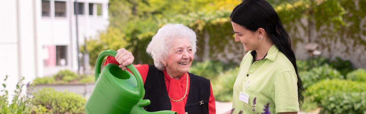 Pflegerin mit Bewohnerin im Garten