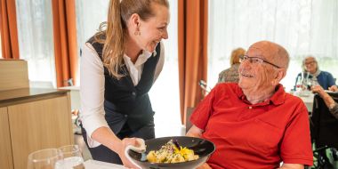 Mitarbeiterin serviert Mann Essen