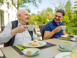Mitarbeiter mit Bewohner draussen am Kaffee trinken