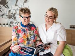 Pflegerin und Bewohnerin lesen im Magazin