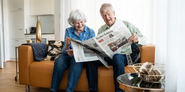 Mann und Frau sitzen auf dem Sofa und lesen die Zeitung