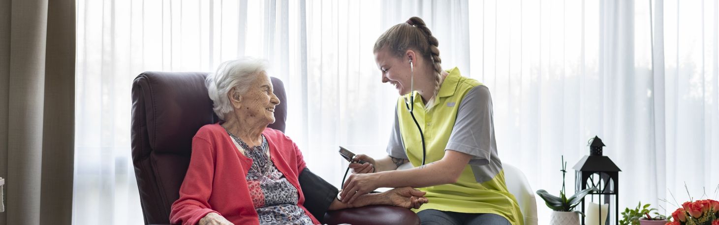 Mitarbeiterin misst Frau Blutdruck