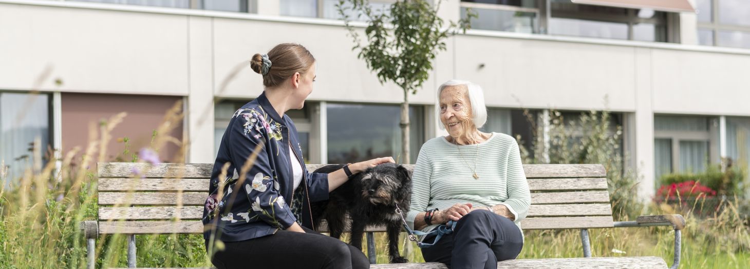 Zwei Frauen auf der Bank mit einem Hund