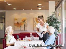 Mitarbeiterin serviert Bewohnende