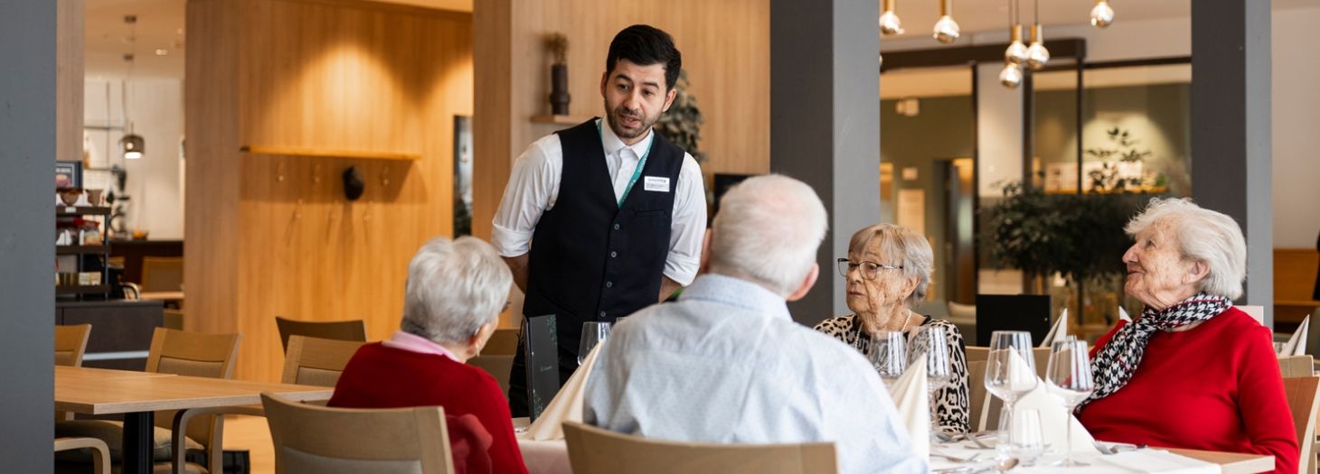 Zwei Herren am Tisch werden vom Servicepersonal zum Mittagessen bedient
