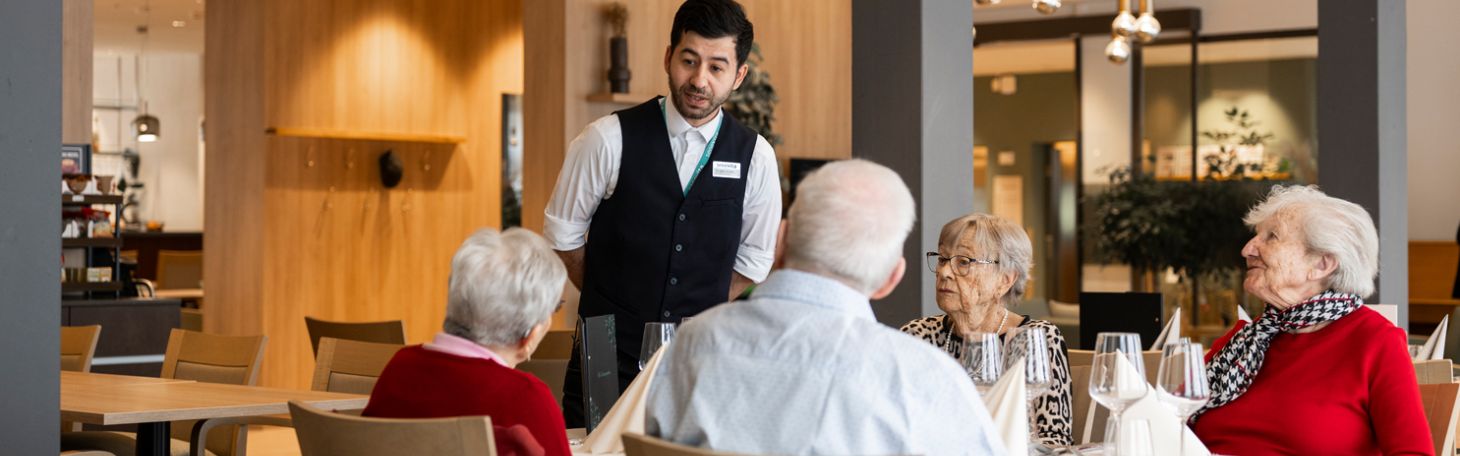 Zwei Herren am Tisch werden vom Servicepersonal zum Mittagessen bedient