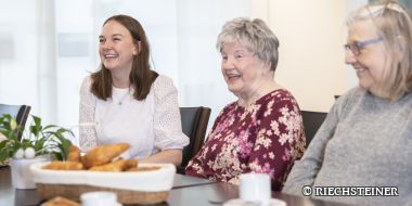 drei Personen lachen am Tisch