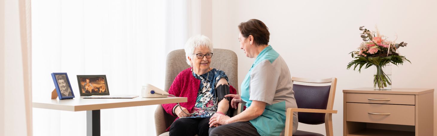 Mitarbeiterin misst Bewohnerin Blutdruck