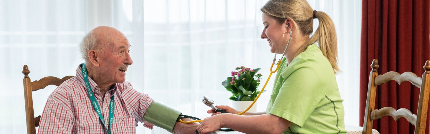 Mitarbeiterin misst Bewohner Blutdruck