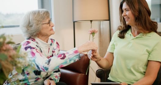 Seniorin überreicht Mitarbeiterin Blumen